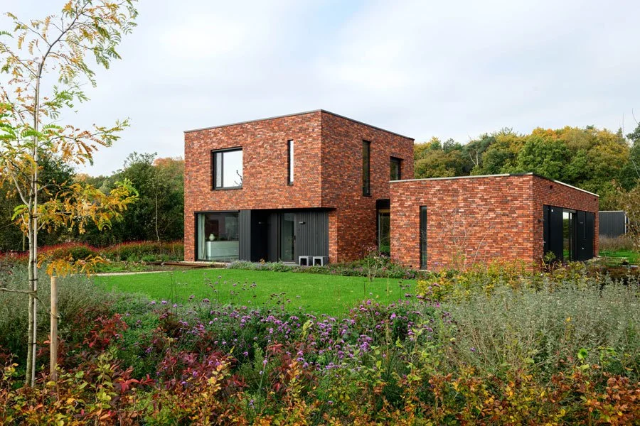 Moderne bakstenen woning met grote ramen en een groene tuin